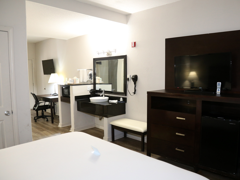 Guest room entertainment center, mini-fridge, vanity, and work desk