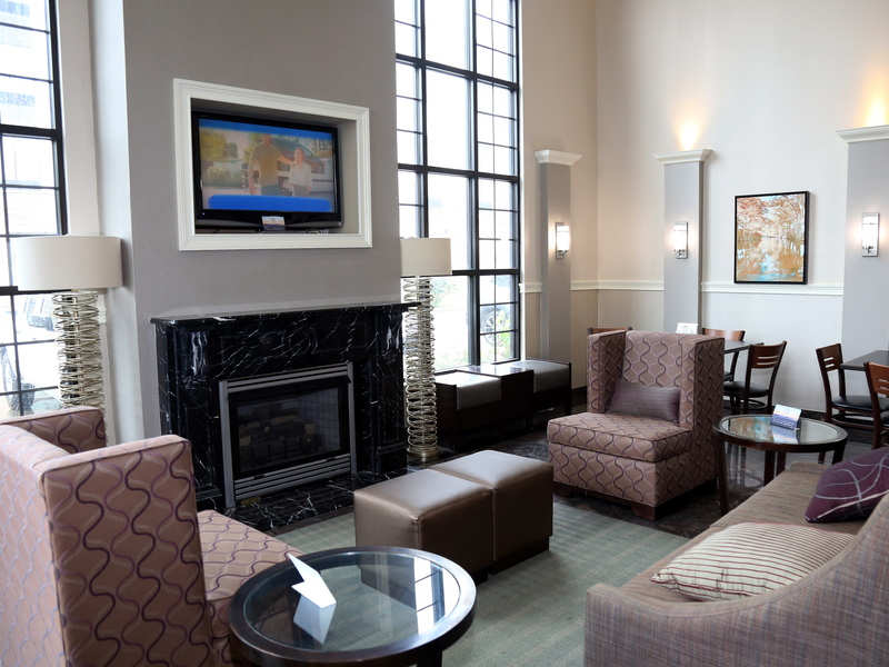 Bright hotel lobby seating area with fireplace and tall windows